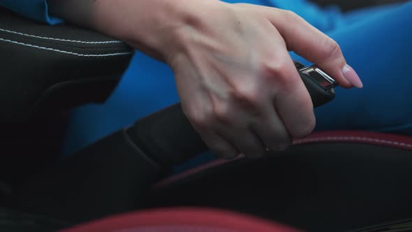 A Womans Hand Presses a Button and Lowers the Handbrake alt