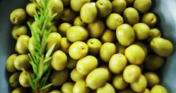 Fresh green olives and rosemary in a bowl alt