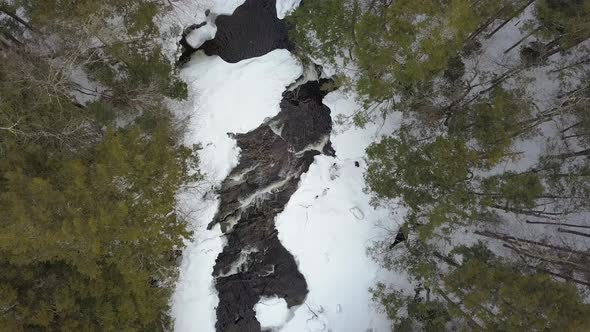 Top down drone shot of snowy river rapids in winter alt