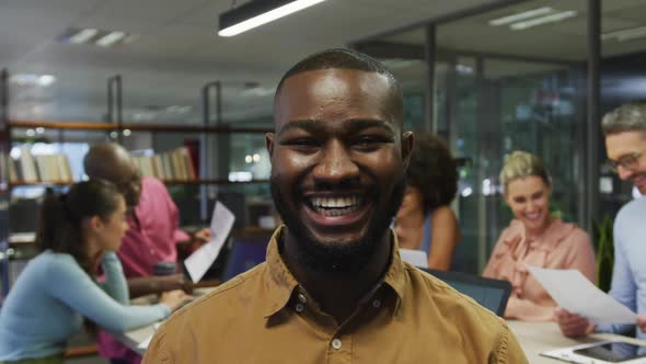 Portrait of african american businessman smiling over diverse business colleagues talking alt