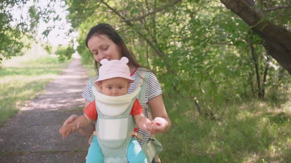 A mother with a newborn baby in a sling walk alt