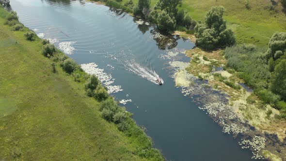  a Small Rubber Fishing Boat with A Motor Is Moving Quickly on A Small River
