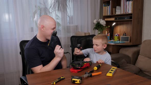 Cheerful Father and Son are Repairing a Toy Car with a Screwdriver alt