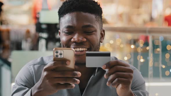 Young Happy Smiling Guy Shopper Client Online Store Customer Makes Purchase Paying By Credit Card alt