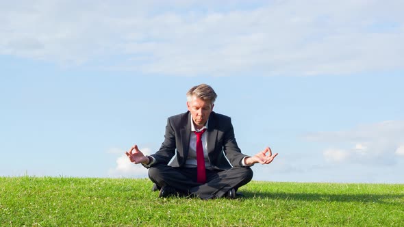 Businessman practicing yoga in the lotus position in a park