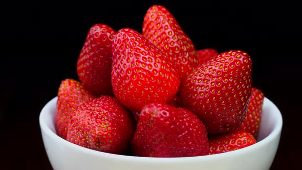 Strawberries without tails lie in white bowl or plate. It rotates alt