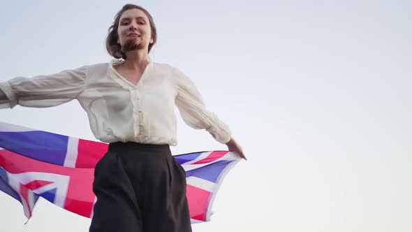 An English Woman with the British Flag Dances in Nature, Success and Happiness