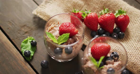 Video of chocolate pudding with strawberries and bluberries on a wooden surface alt