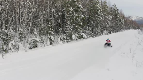 Men on snowmobile having fun and riding in winter scenery alt