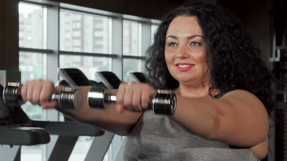 Happy Plus Size Sportswoman Lifting Dumbbells at the Gym