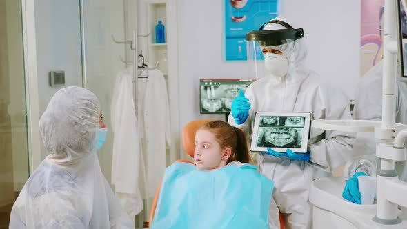 Dentist with Face Shield Explaining Panoramic Mouth Xray Image to Mother of Kid alt