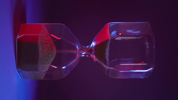 Glass Hourglass with Golden Sand on Purple Background alt