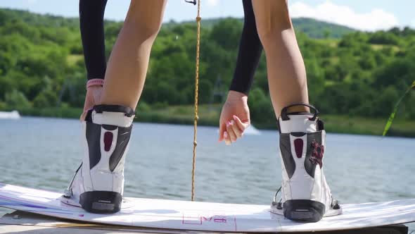 Close Up of Woman Binding Boots of Wakeboarding Board alt