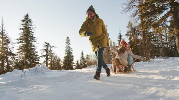 Friends Having Fun Sledding In Forest alt