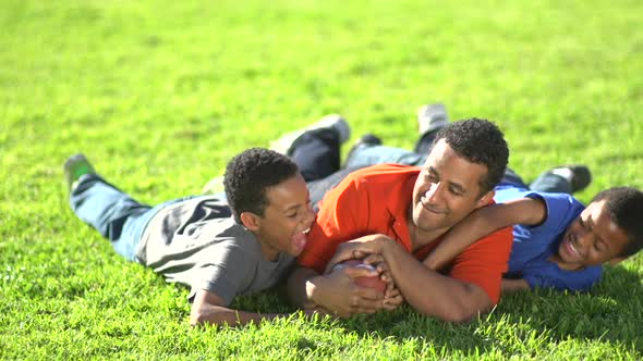 Group portrait of a father and his sons with a football alt