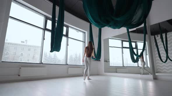 A Young Woman in Slow Motion Prepares to Begin a Stretching and Yoga Class on a Hammock alt