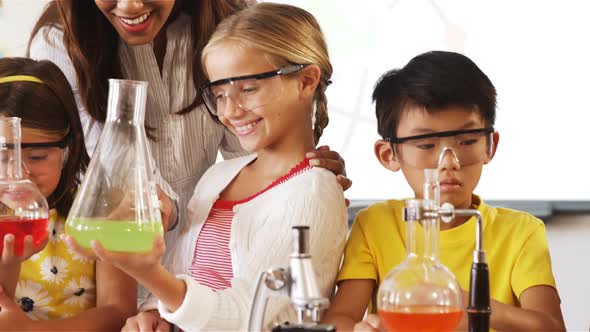 School kids doing a chemical experiment in laboratory alt