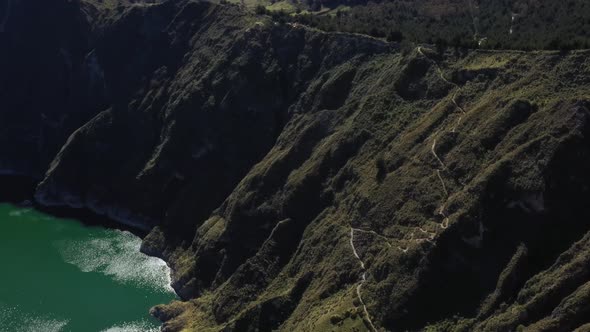 Aerial view of the Quilotoa lake  showing the side of the lake and a trail going down the crater alt