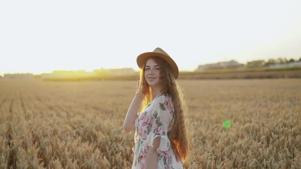 Young, Long-haired Girl Wore in Dress and Hat, Poses at Camera Among Wheat alt