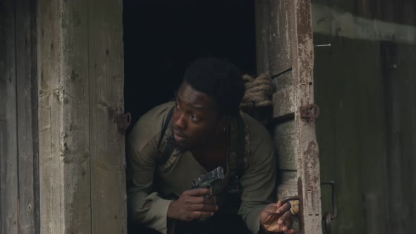 African Man with Gun Leaving Shack Hiding From Zombie in Abandoned Territory alt