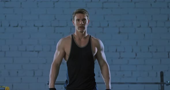 Muscular Male Athlete Stands and Breathes Deeply After Exercise in the Gym alt
