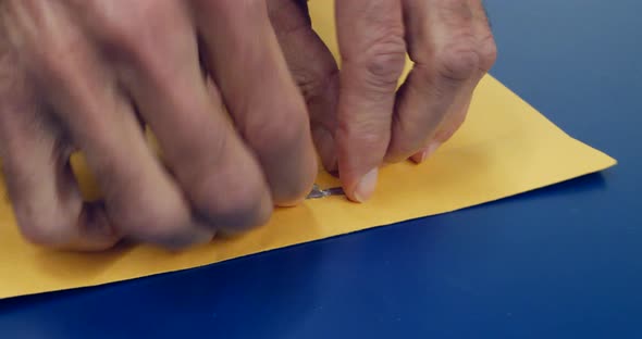Close up on hands opening a yellow envelope with important document inside after being mailed and de alt