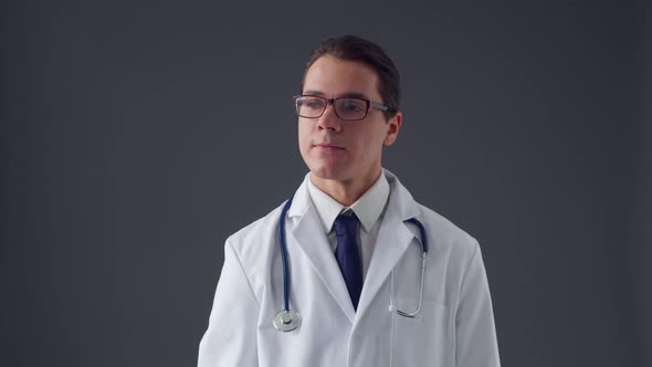 Studio portrait of young professional medical doctor standing over grey background alt