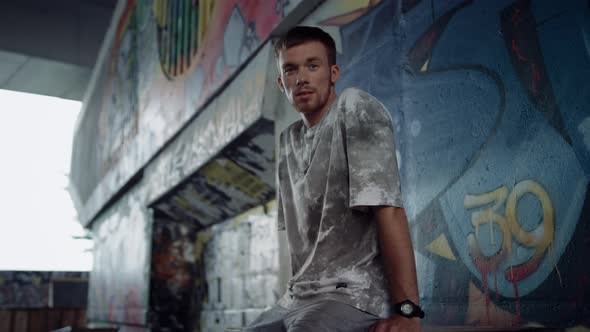 Young Roller Skater Resting After Skating at Skate Park with Graffiti Wall alt