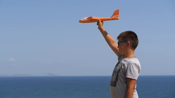 Boy with a Toy Airplane in His Hands on the Background of the Sea alt