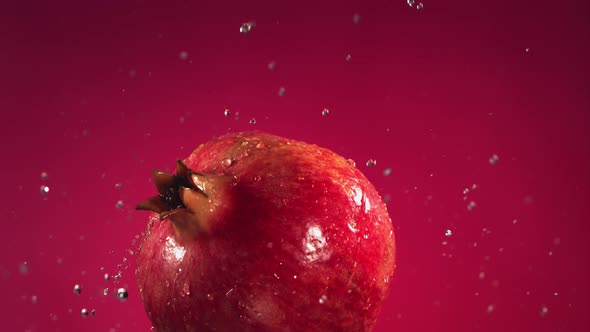 Flying of Pomegranate in Fuchsia Background in Slow Motion alt