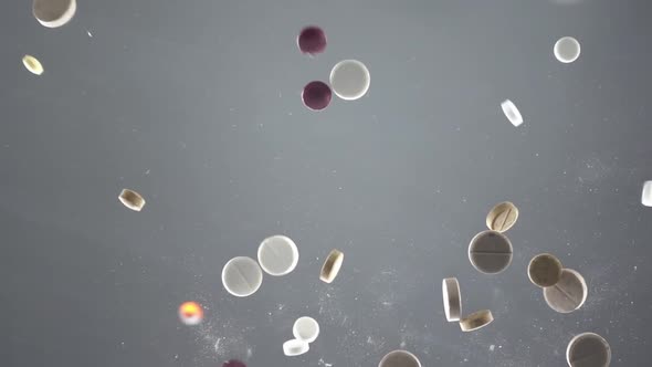 Mixed Pills on Grey Background Seen From Below Are Falling on Glass Surface in Slow Motion alt