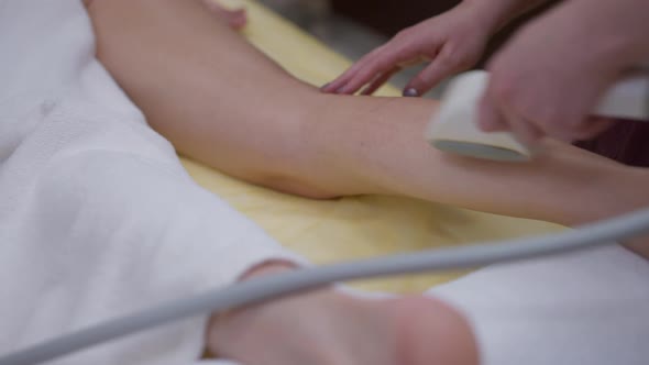 Unrecognizable Masseur Massaging Slim Female Leg with Anticellulite Device alt