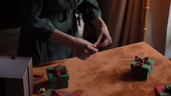 woman preparing card in envelope and gifts for christmas at home on the table