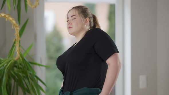 Side View Portrait of Concentrated Young Overweight Woman Doing Shoulder Rolls Warming Up in the alt