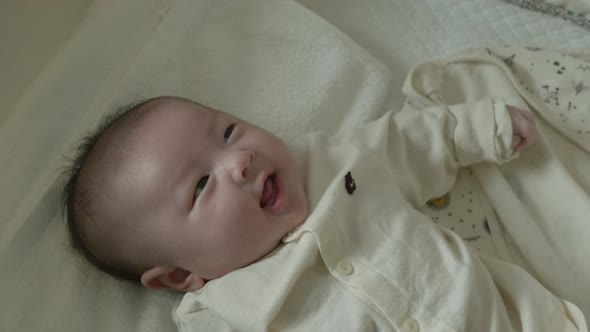 The face of a baby smiling broadly while looking at the mobile. alt