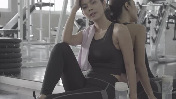Beautiful young asian woman after workout with tired and exhausted in the gym. alt