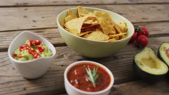 Video of tortilla chips, guacamole and salsa dip on a wooden surface alt