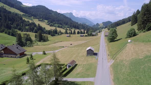 Aerial View of a Valley in Switzerland with Chalets and a Mountainous Landscape alt