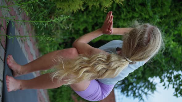Woman Trains on the Street in the Evening Does Yoga Vertical View alt