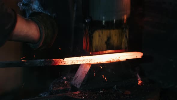 Closeup of Hydraulic Hammer Shaping Piece of Hot Iron. Blacksmith Making Blades for Knifes in His alt
