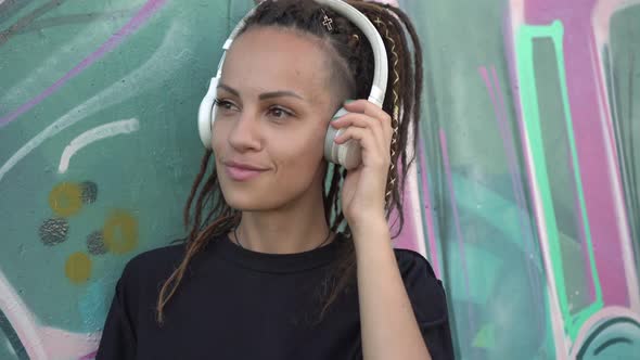 Modern Teenage Woman with Dreadlocks Listens to Music on Headphones alt