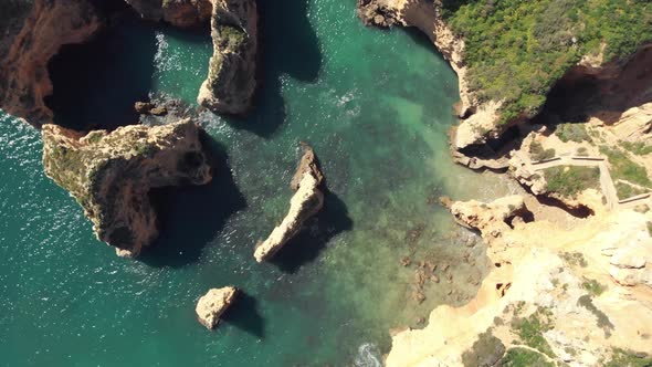 Birds eye view over Rugged jagged Algarve Coastline, In Lagos, Portugal - Aerial Top rotation shot alt