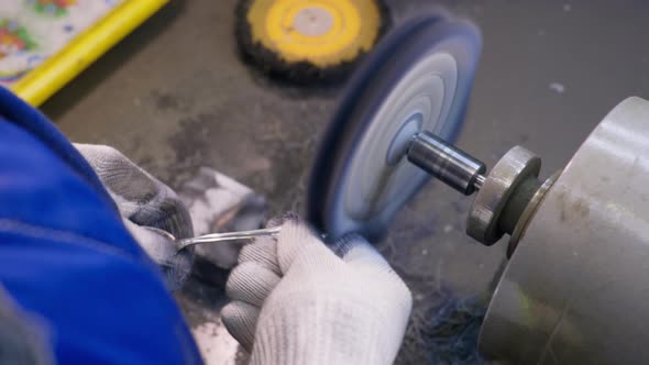 Close Up at the Worker Polishing the Finished Silver Spoon with a Machinetool at the Plant for alt