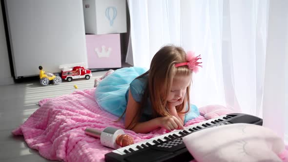 girl with a crown on her head, lies on a bed,  plays on a children is synthesizer.