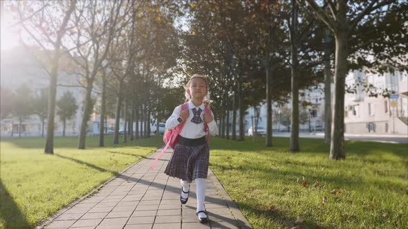 Young Girl in School Uniform Is Walking in the Park at Sunny Weather, Steadicam. alt