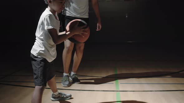 Male Basketball Player Teaching Boy to Dribble Ball alt