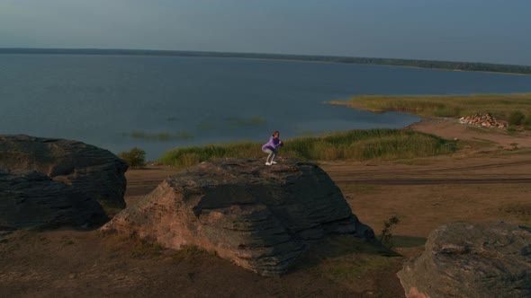 A Girl is Doing Fitness on a Hill on the Lake Shore alt