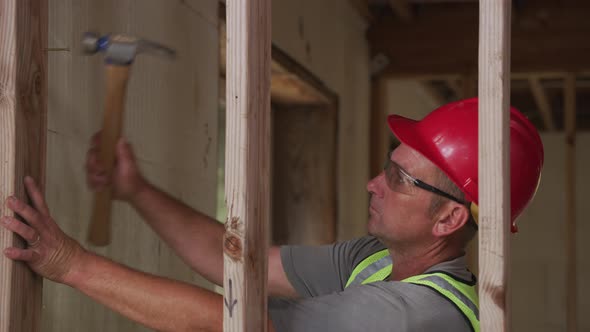 Construction worker nailing wall studs