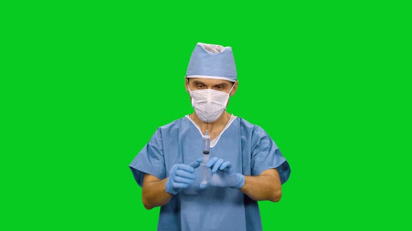 Male Anesthetist In Mask Preparing A Syringe For Injection on Green Screen