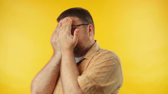 Scared upset caucasian man covering face and eyes with hands, hiding from fear alt